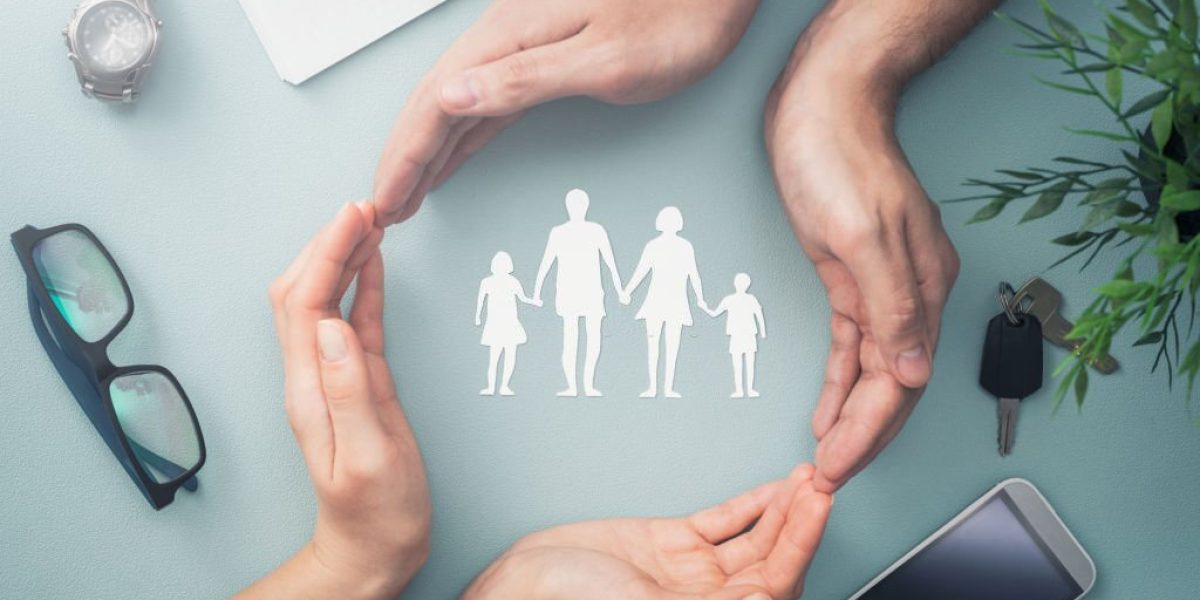 Hands with cut out paper silhouette on table. Family care concept.