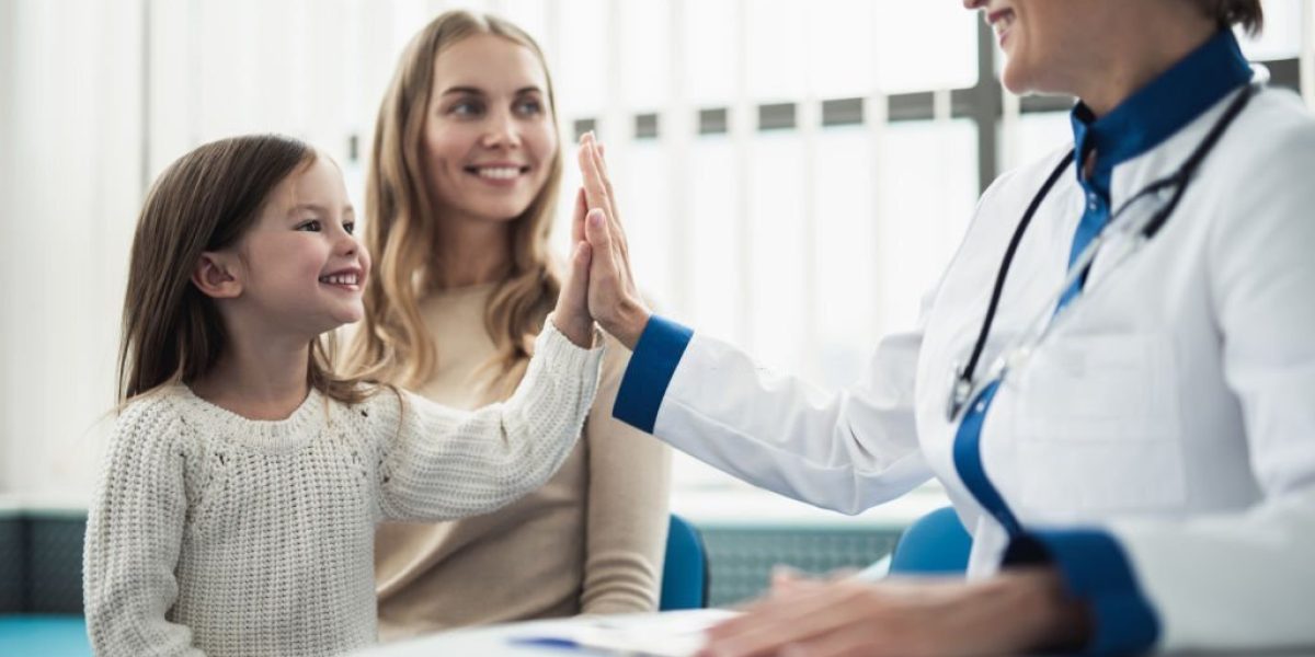 Concept of trustworthy method of consultation in healthcare system. Waist up portrait of smiling little girl giving five to pediatrician lady in medical cabinet