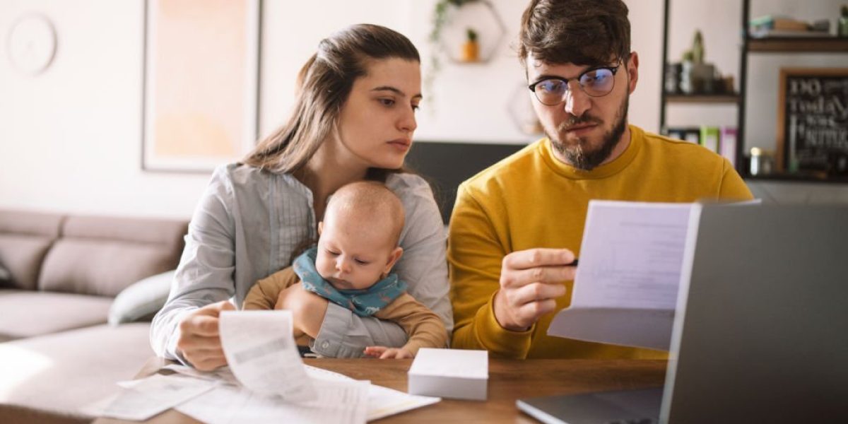Young family with baby worried about family budget and high taxes and bills. Inflation concept.